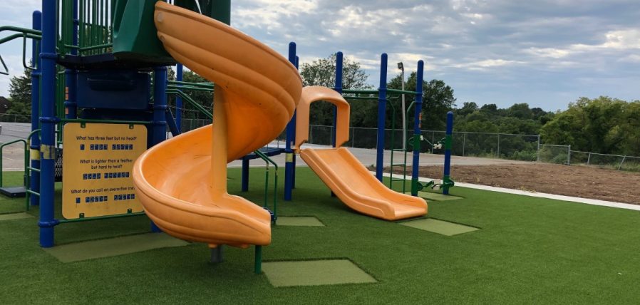 Yellow slide installed on artificial grass from SYNLawn