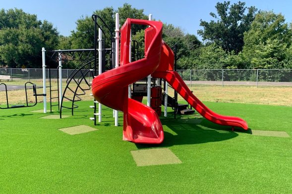 Red slide installed on artificial playground grass