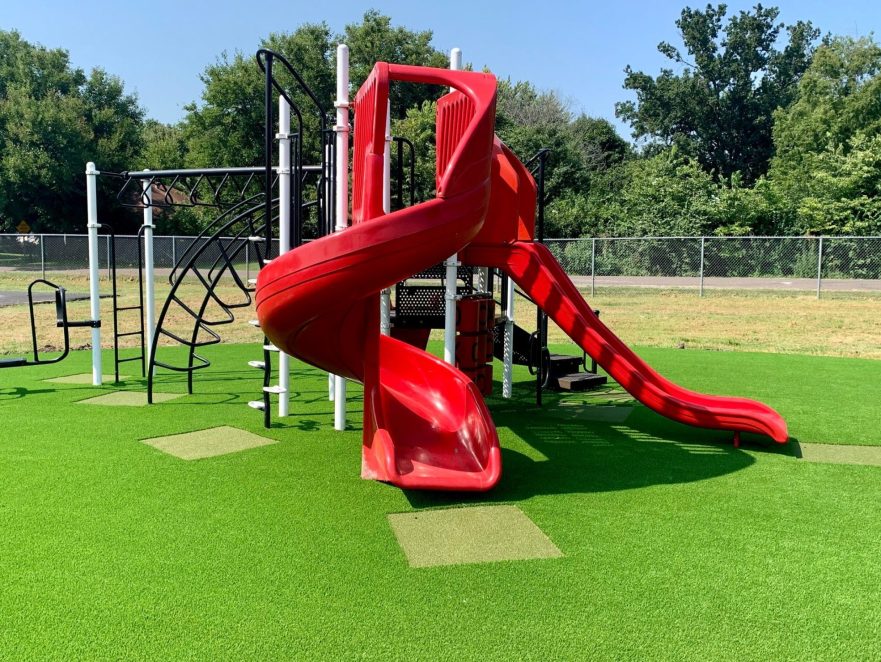 Red slide installed on artificial playground grass